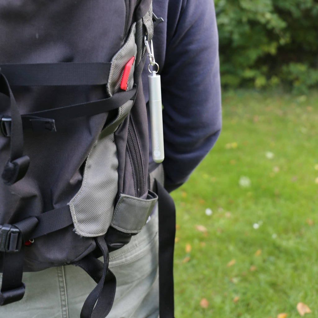 Leafera :Person wearing a black backpack with a grassy background