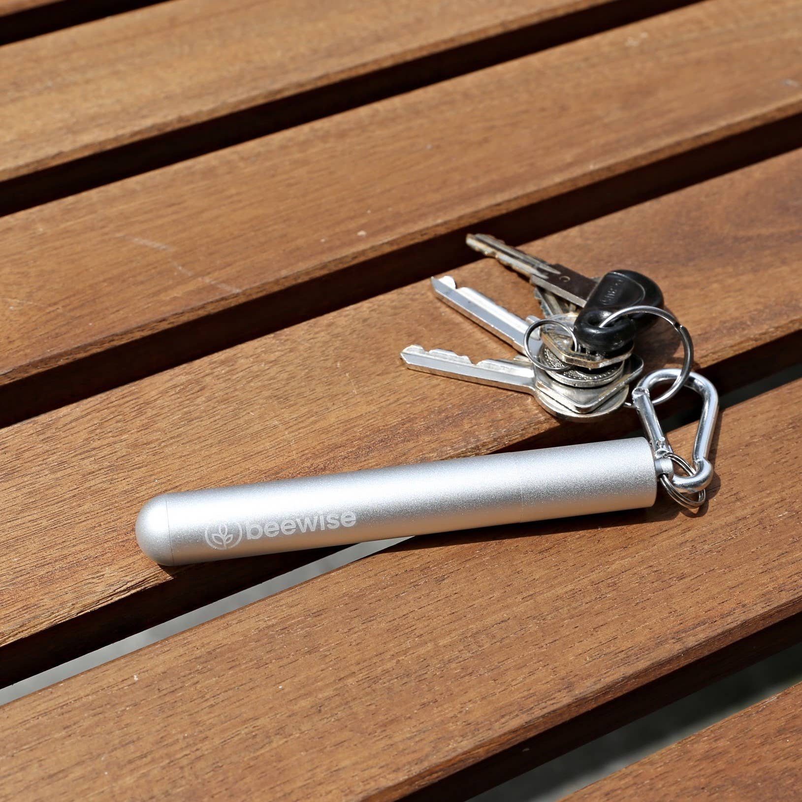 Leafera - Silver keychain tool with 'beewise' branding on a wooden surface